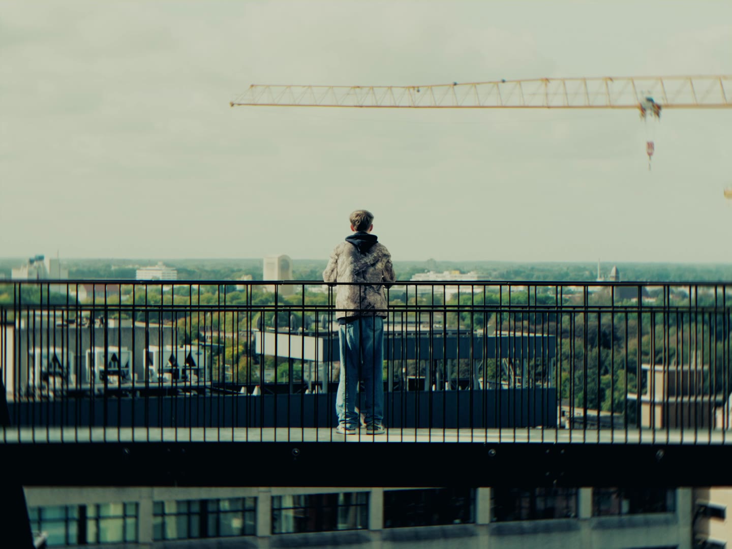 Figuur op een balkon onder een bouwkraan