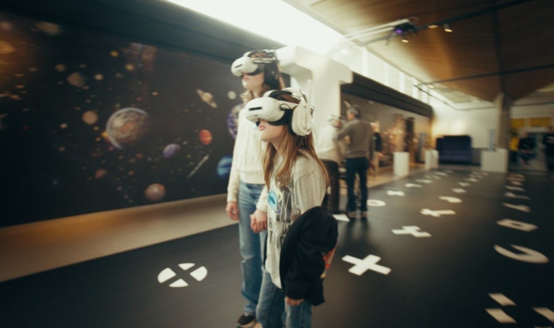 Bezoekers met VR-brillen voor een wand vol planeten